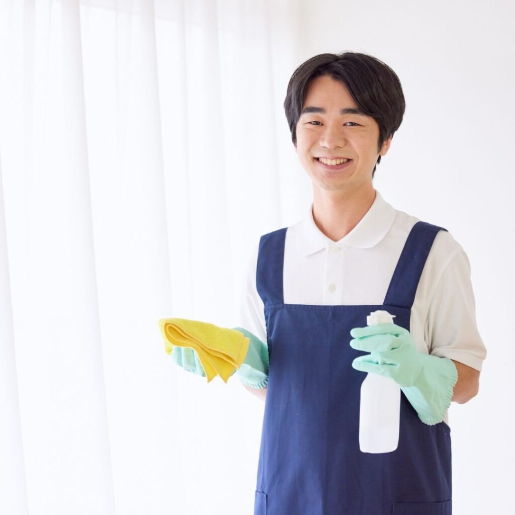 Man in cleaning uniform holding spray bottle and cloth ready for cleaning